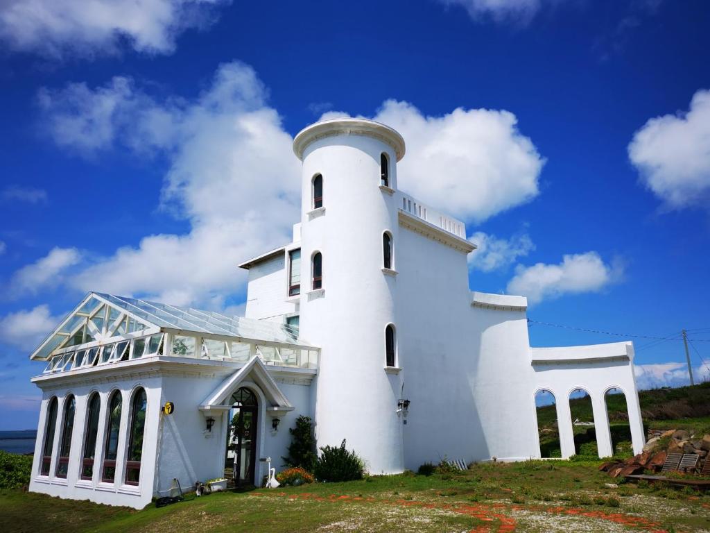 a white lighthouse on a hill with a blue sky at 23.5 Blue B&B in Xiyu