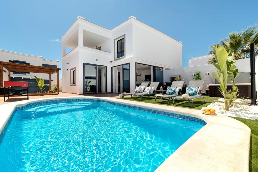 a villa with a swimming pool in front of a house at Villa Acacia in Yaiza