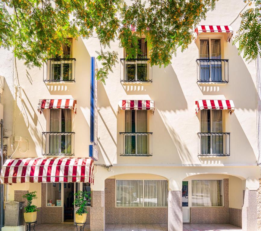un edificio de apartamentos con toldos rojos y blancos en Residencial Capri by Umbral, en Albufeira
