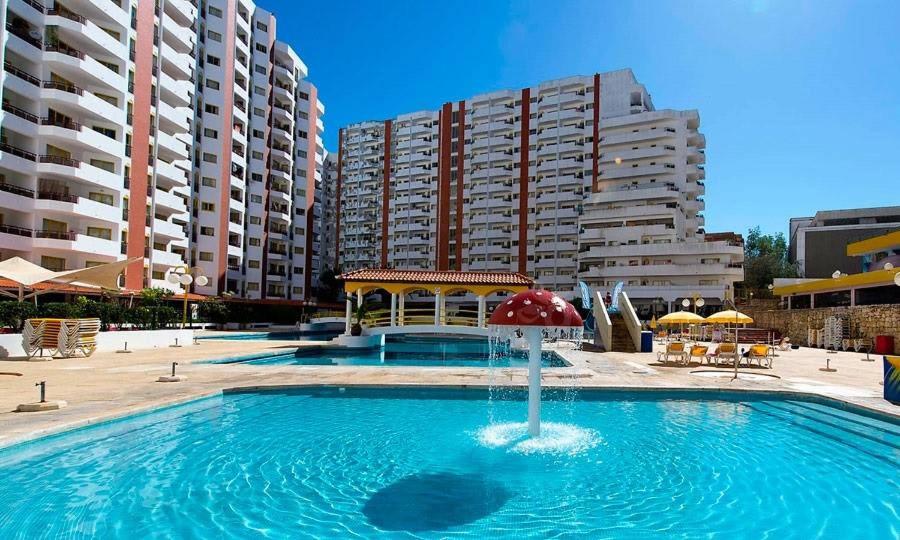 - une piscine avec un parasol et quelques bâtiments dans l'établissement River View, à Portimão