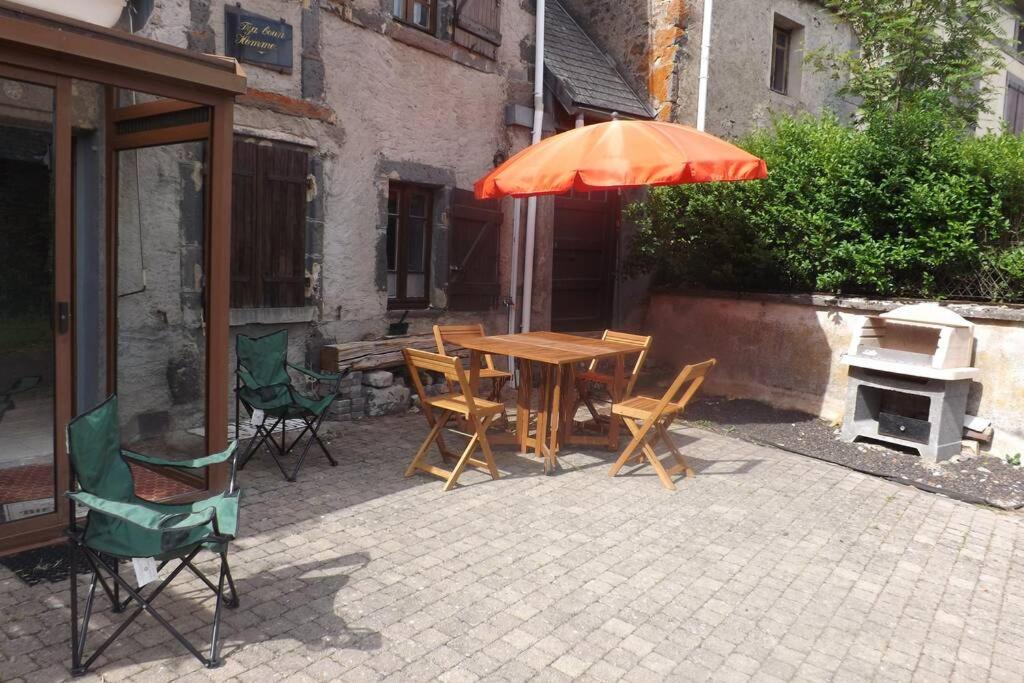 einen Holztisch und Stühle mit einem orangenen Regenschirm in der Unterkunft Maison de montagne in Le Vernet-Sainte-Marguerite