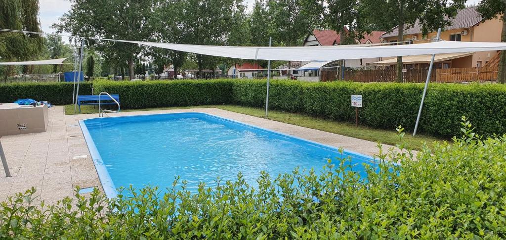 a large blue swimming pool with a white canopy at Stég Stúdió Stb. . in Balatonberény