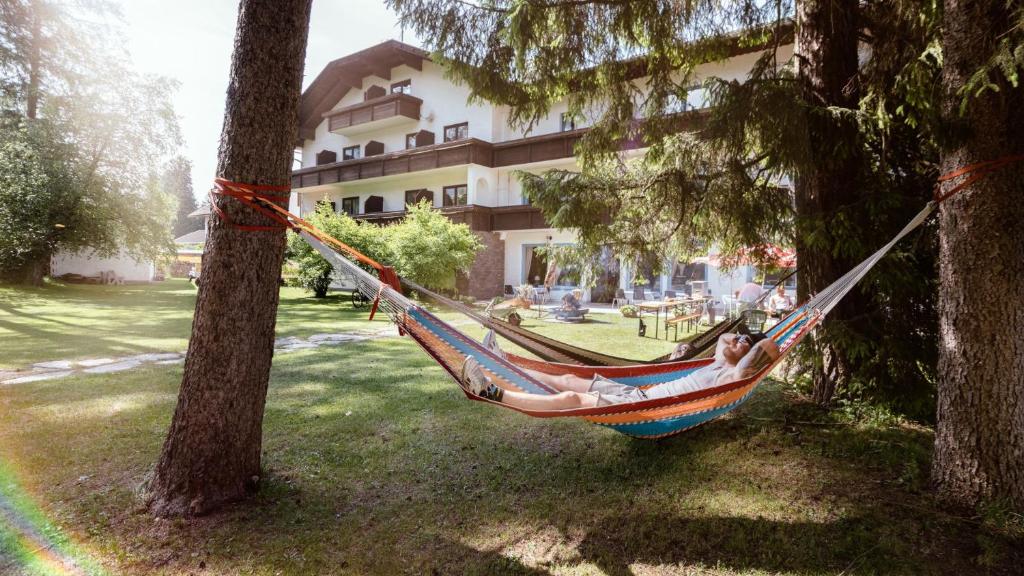德勞塔爾貝格的住宿－Drauradweg Hostel，两个人躺在两棵树之间的吊床上