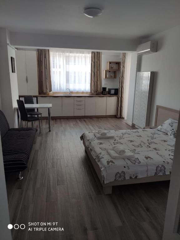 Cet appartement comprend une chambre avec un lit et une table ainsi qu'une cuisine. dans l'établissement STUDIO LOTUS, à Mamaia