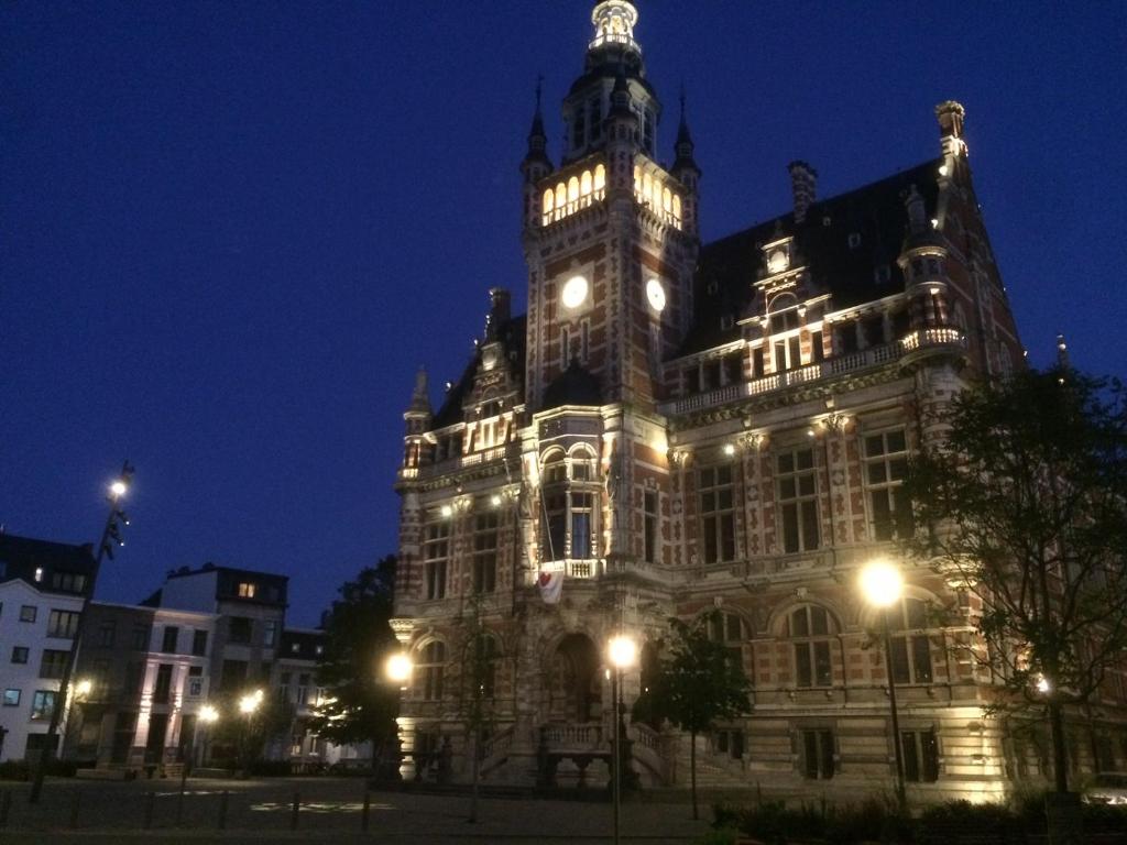 um grande edifício com uma torre de relógio à noite em Borgerhouse B&B em Antuérpia
