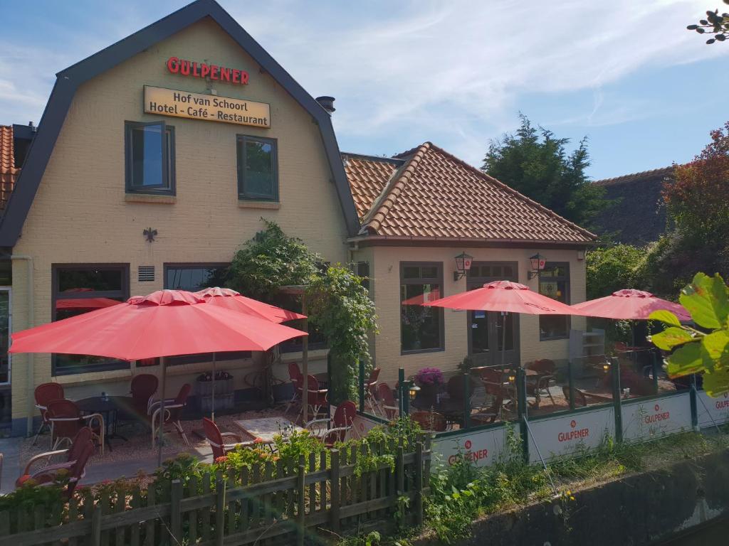 a restaurant with red umbrellas in front of a building at Hof van Schoorl in Schoorldam