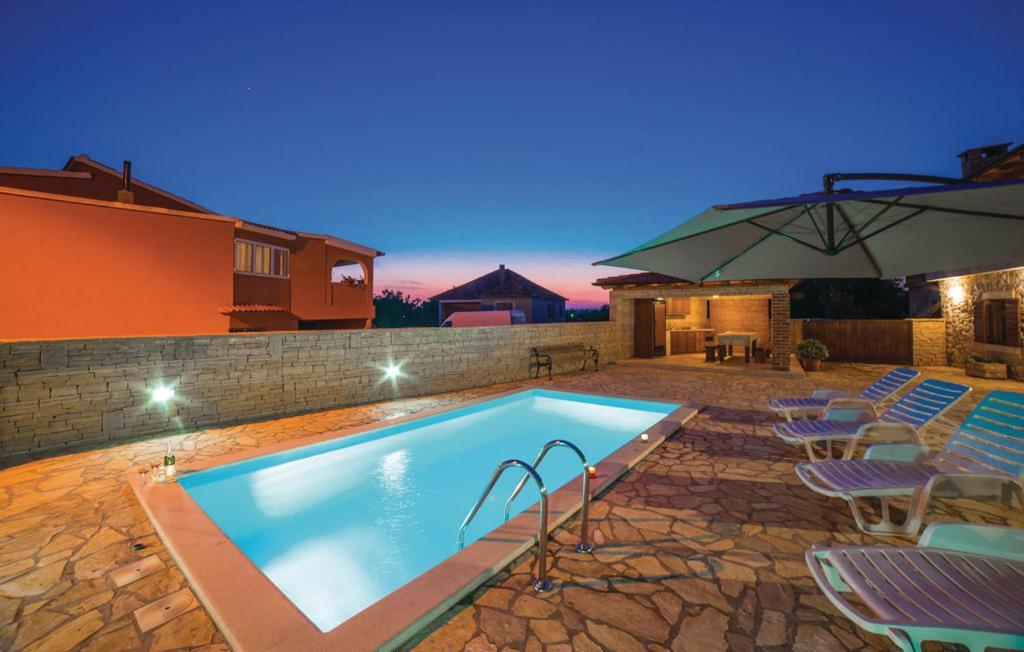 a swimming pool with chairs and an umbrella at Luxury Villa Maria with Pool in Galovac