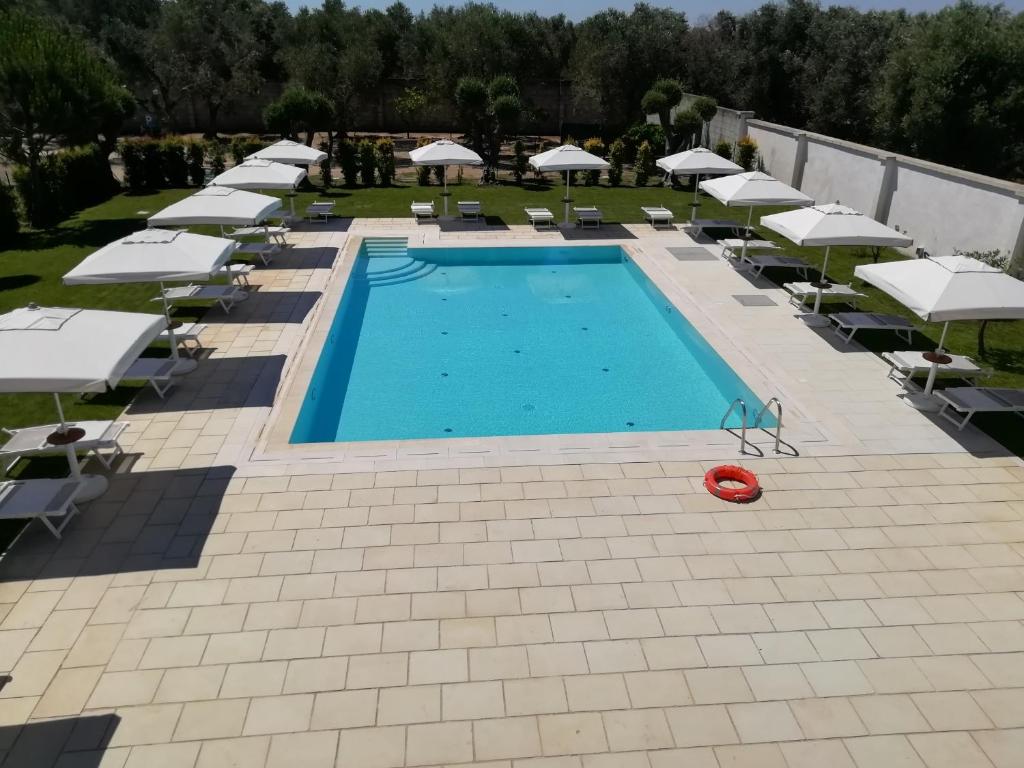 an overhead view of a swimming pool with chairs and umbrellas at Masseria Carrozzi in Melendugno