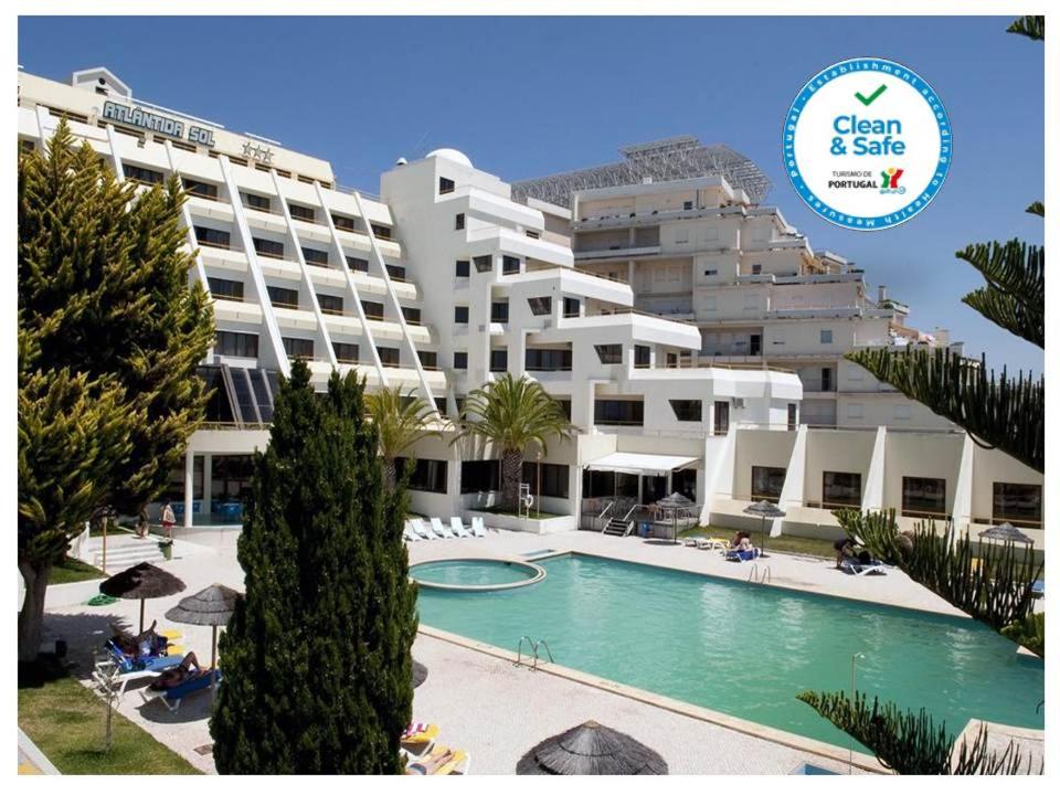 ein großes Apartmenthaus mit Pool davor in der Unterkunft Hotel Atlantida Sol in Figueira da Foz