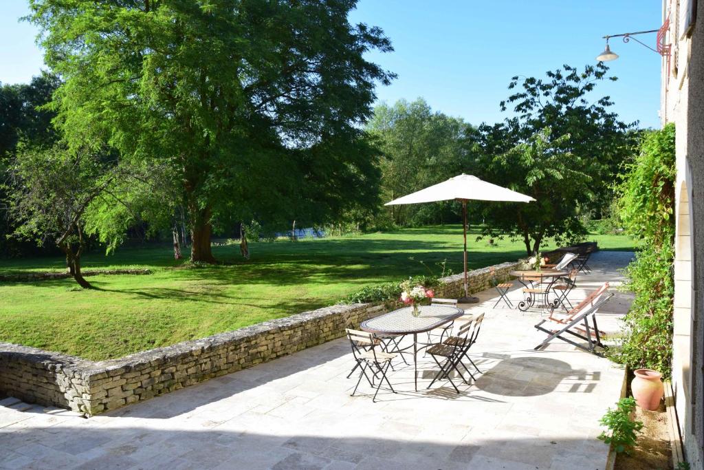 un patio con mesas, sillas y una sombrilla en Moulins de Clan, en Jaunay-Clan