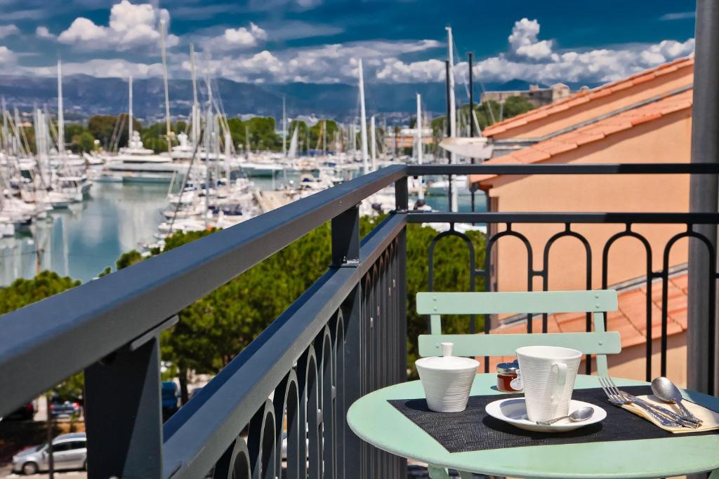 a table on a balcony with a view of a marina at Hôtel La Villa Port d'Antibes & Spa in Antibes