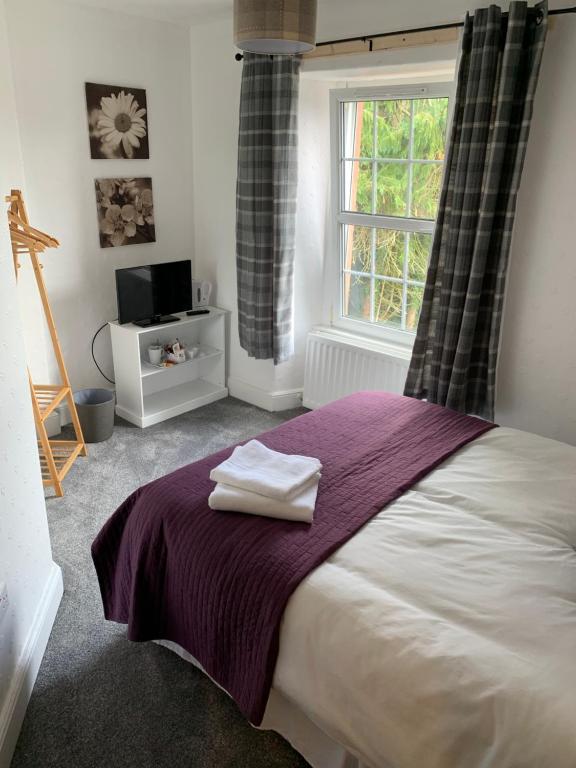 a bedroom with a bed with a purple blanket and a window at DOVENBY SHIP in Tallentire