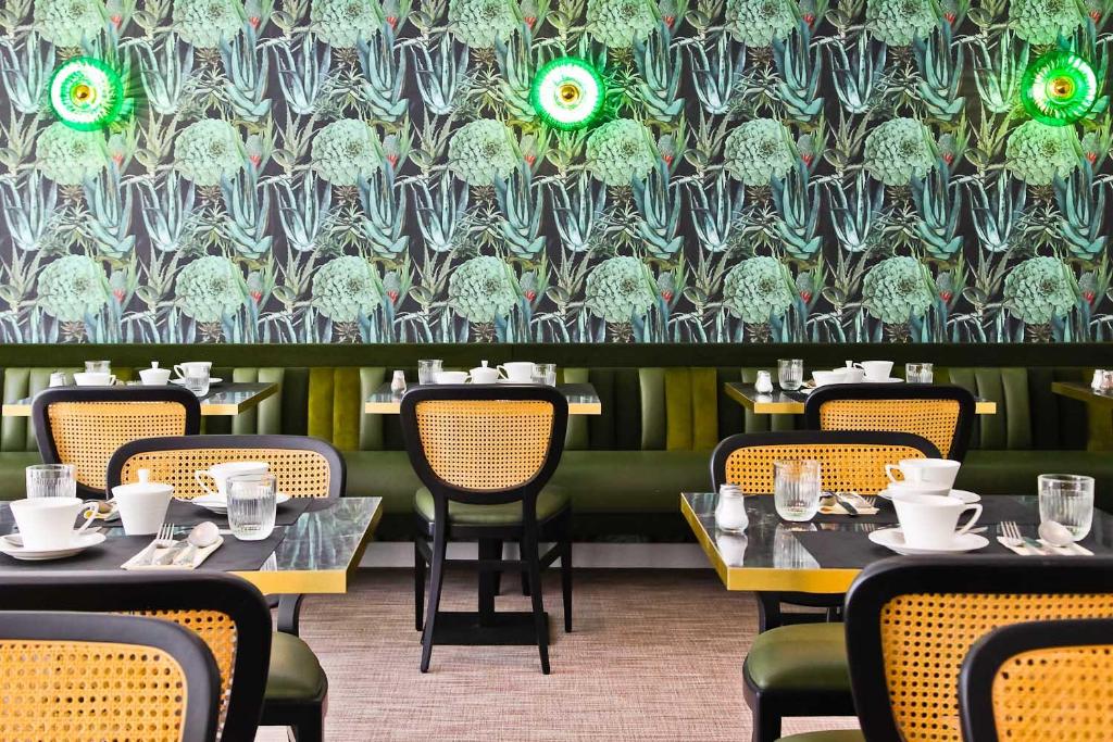 a dining room with tables and chairs and a floral wall at Hôtel La Villa Port d'Antibes & Spa in Antibes