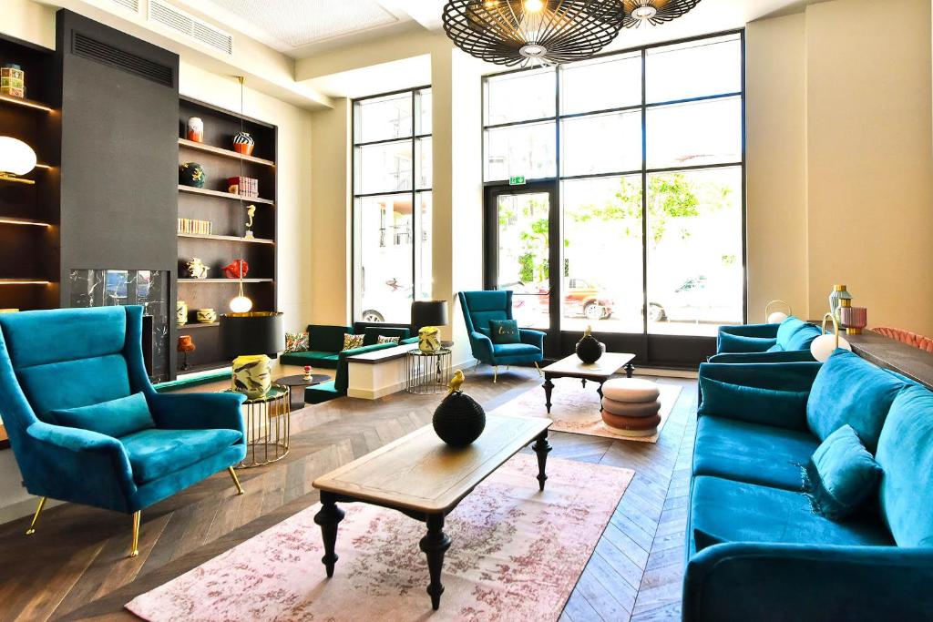 a living room with a blue couch and chairs at Hôtel La Villa Port d'Antibes & Spa in Antibes