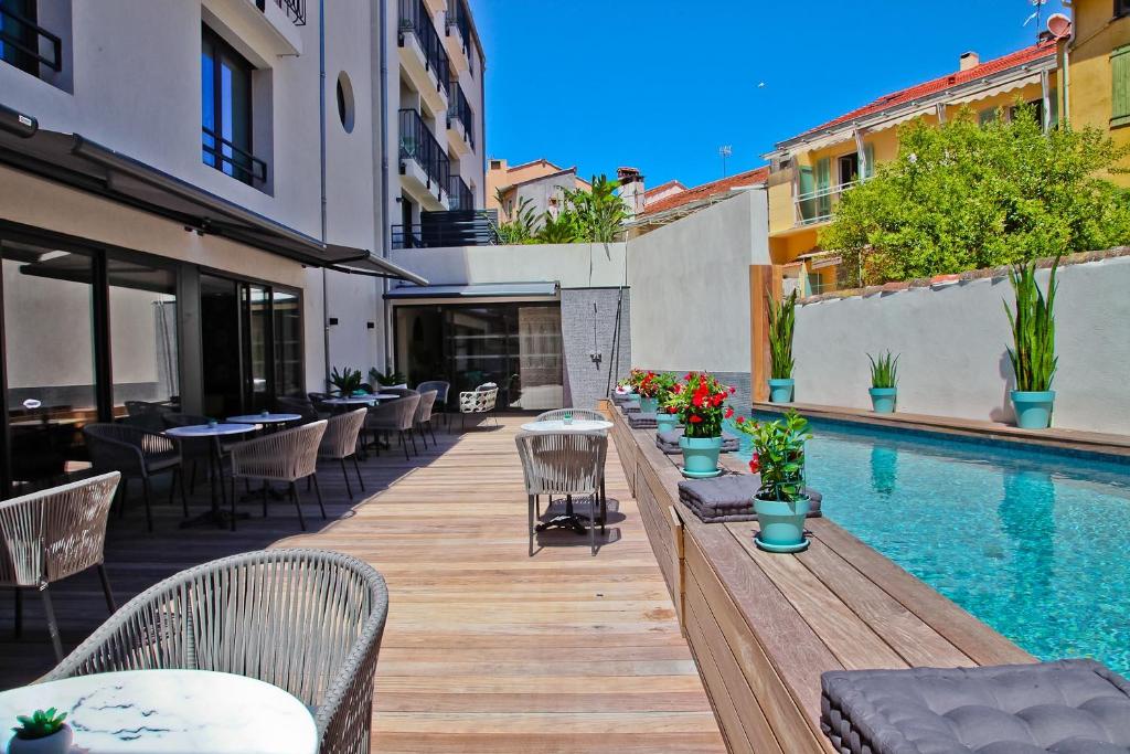 a patio with tables and chairs next to a swimming pool at Hôtel La Villa Port d'Antibes & Spa in Antibes
