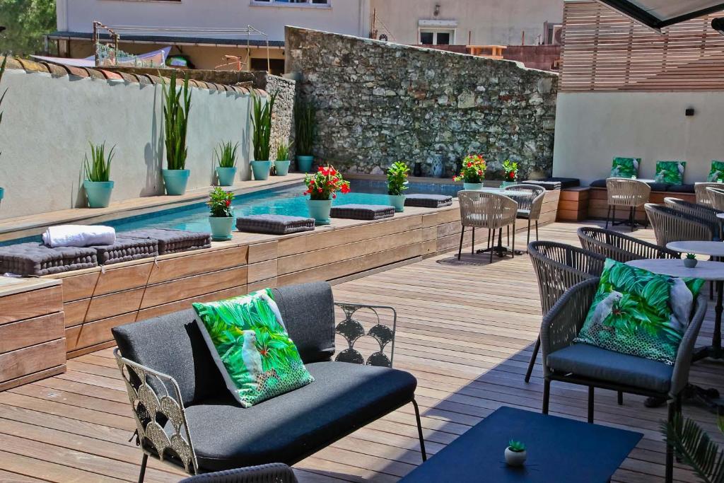 a patio with chairs and tables and a swimming pool at Hôtel La Villa Port d'Antibes & Spa in Antibes