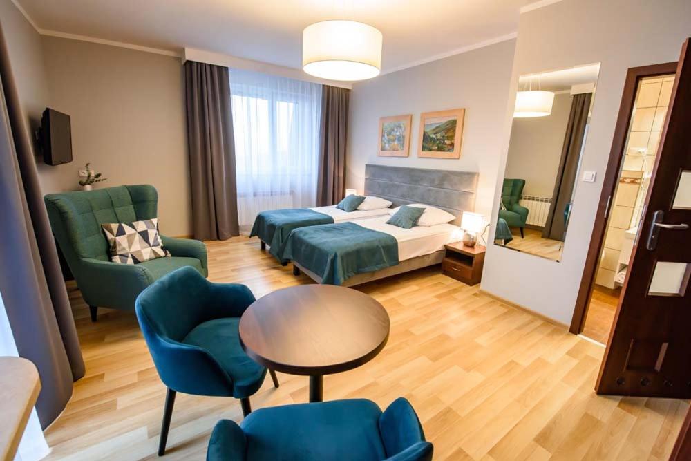 クリニツァ・ズドルイにあるOśrodek Szkoleniowo Wypoczynkowy Galicyaのベッド、テーブル、椅子が備わるホテルルームです。
