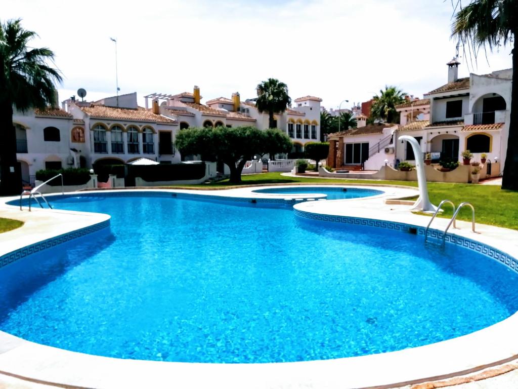 een zwembad met blauw water voor een huis bij Bungalow de vacaciones in Torrevieja