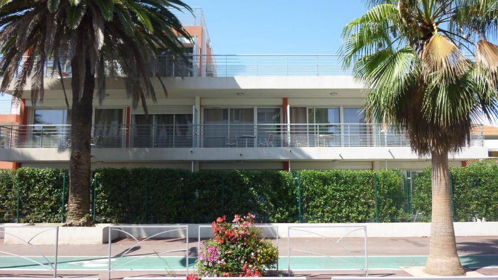 a building with palm trees in front of it at Residence Syracuse in Villeneuve-Loubet
