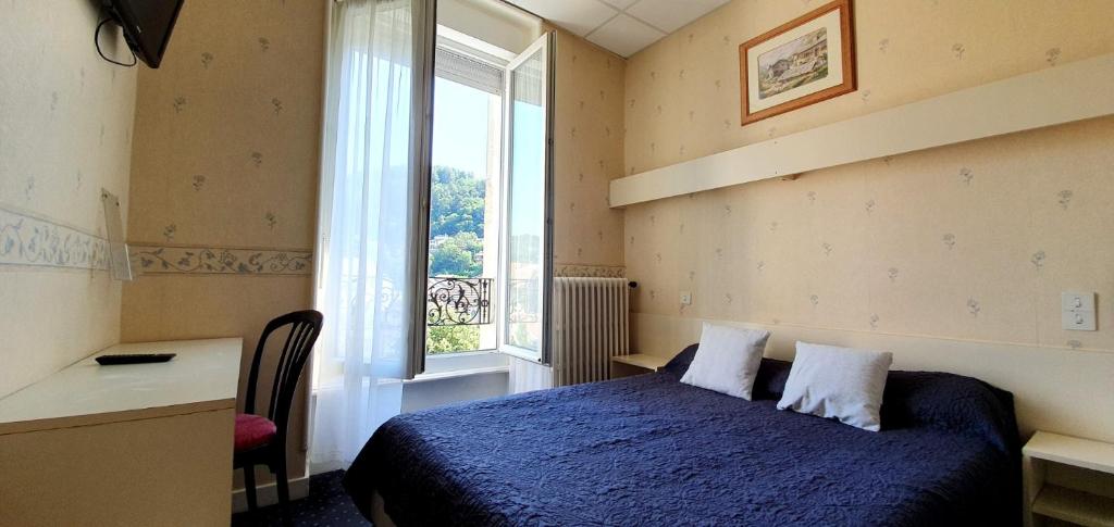 a bedroom with a blue bed and a window at Hôtel Saint Jean in Vals-les-Bains