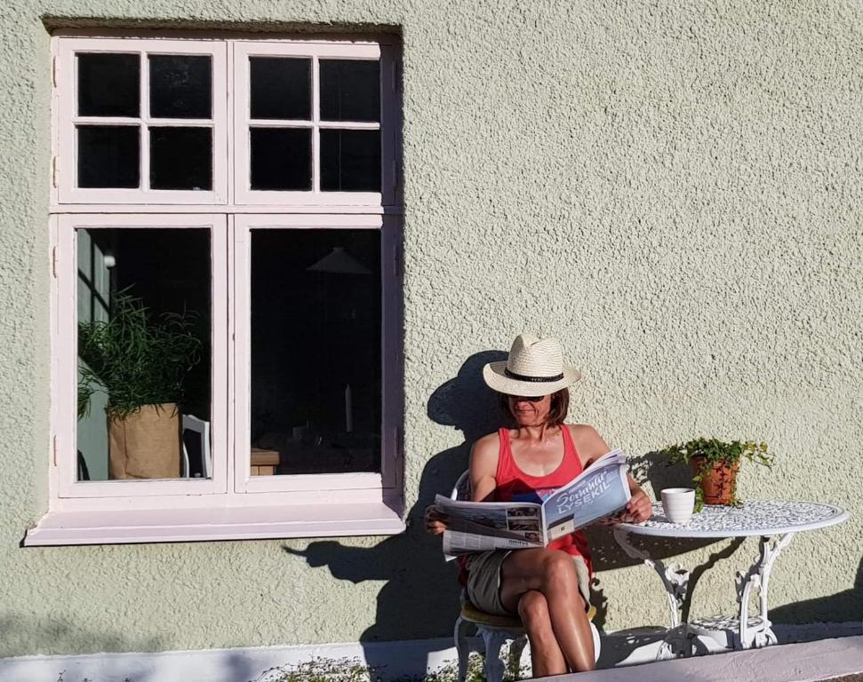 a woman sitting at a table reading a book at Havings skafferi in Lysekil