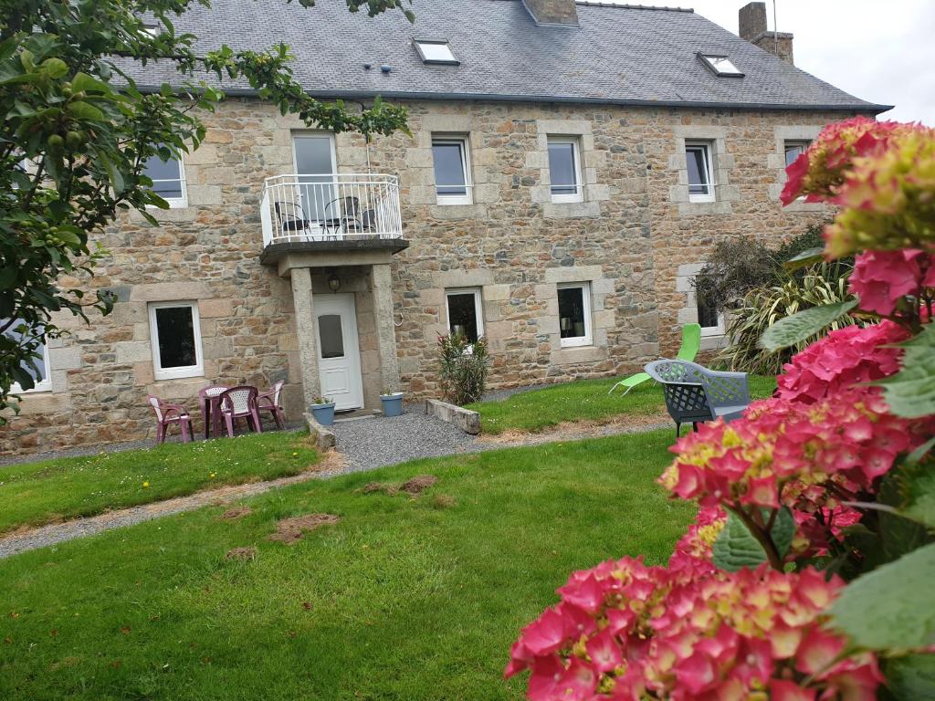 una gran casa de piedra con un patio con flores rosas en Chambres d'Hôtes de la Presqu'Île, en Pleubian