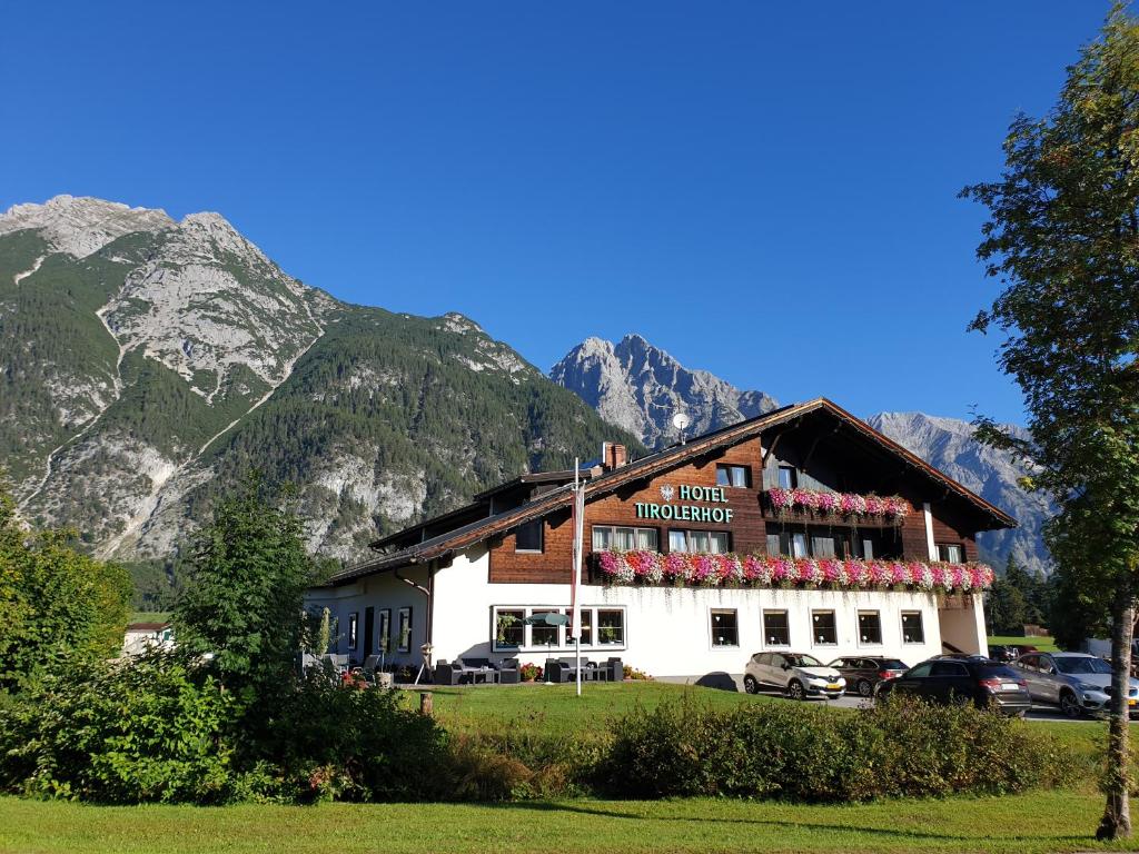 a building with flowers in front of a mountain at Hotel Tirolerhof in Leutasch