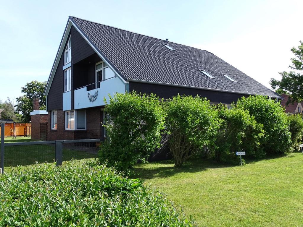 une maison noire et blanche avec des buissons devant elle dans l'établissement 50108 Ferienhaus Cliner Sünn Whg. Baltrum, à Carolinensiel