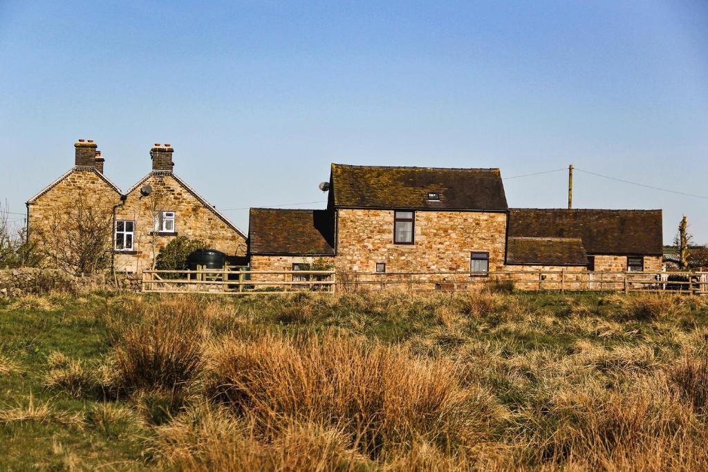 une ancienne maison en pierre sur une colline dans un champ dans l'établissement Moorland View Farm B&B, à Oakamoor