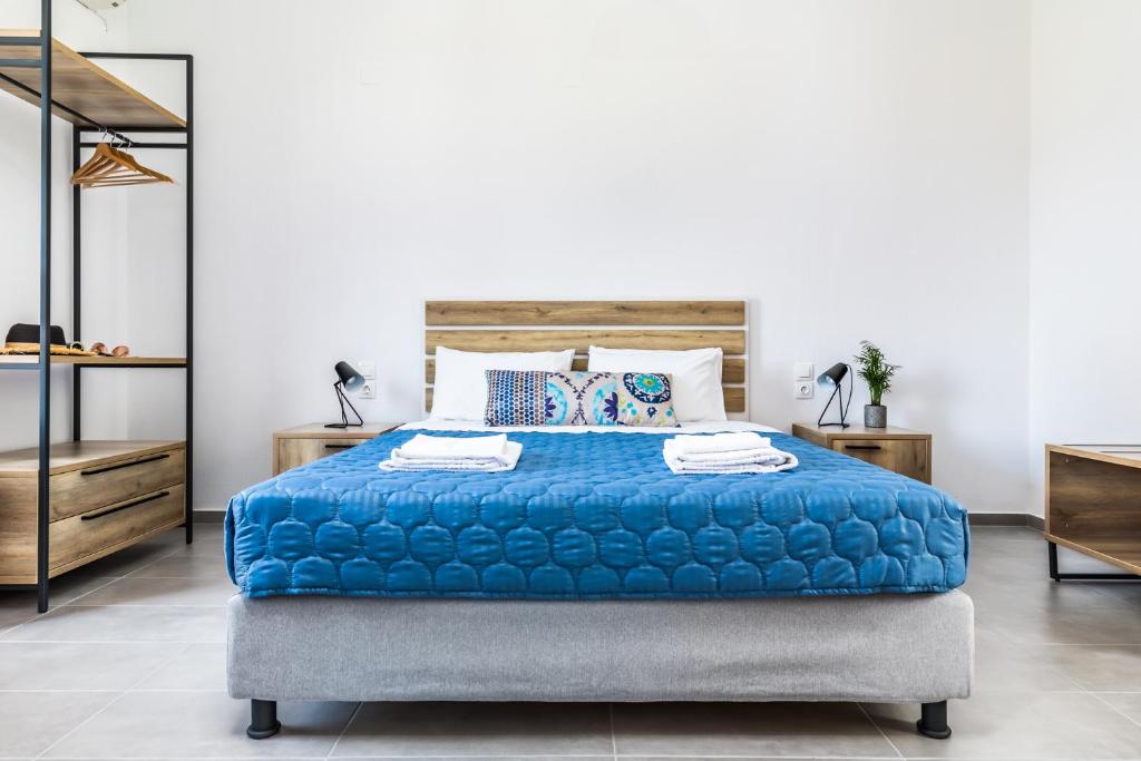 1 dormitorio con 1 cama azul y 2 mesitas de noche en Nepheles, en Skopelos Town