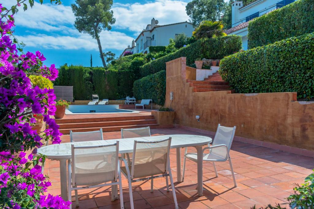 un patio con tavolo, sedie e fiori viola di L-3 CALELLA DE PALAFRUGELL 5/ 6 PAX a Calella de Palafrugell