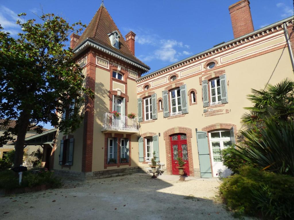 ein großes Backsteingebäude mit einer roten Tür in der Unterkunft Chambre d'Hôtes Bastide du Cosset in Barcelonne-du-Gers