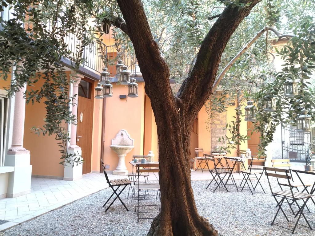 um pátio com mesas e cadeiras e uma árvore em Ca' due Olivi em Toscolano Maderno