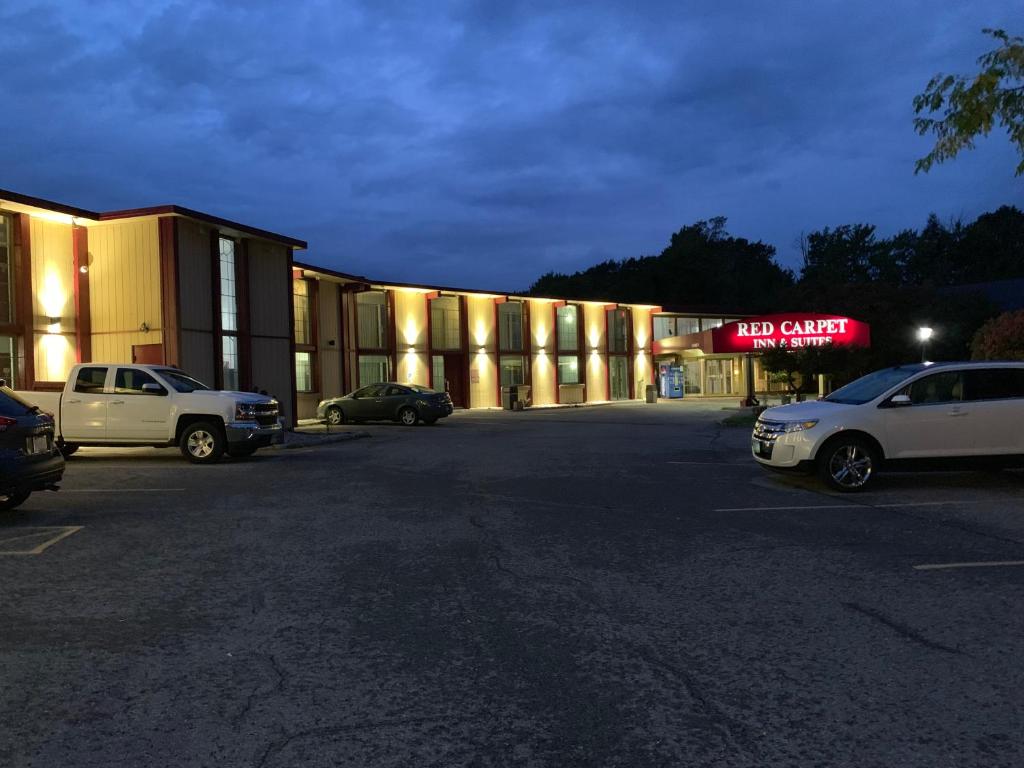 un grand bâtiment avec des voitures garées dans un parking dans l'établissement Red Carpet Inn & Suites Ebensburg, à Ebensburg