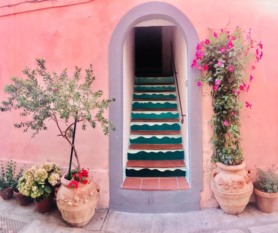 un edificio rosa con scala con piante e fiori di Appartamento chic Marciana Marina (Isola d’Elba) a Marciana Marina