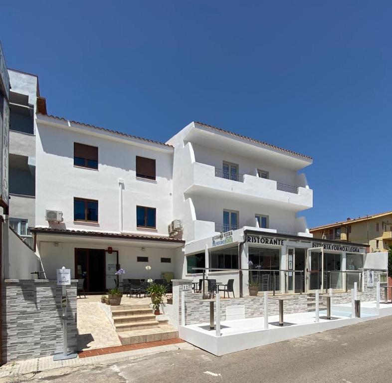 een wit gebouw met een restaurant ervoor bij Hotel Sandalion in Santa Teresa Gallura