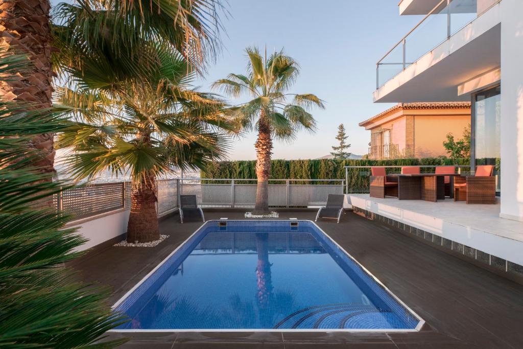 una piscina en el patio trasero de una casa con palmeras en Nevada Granada Relax & Nature, en La Zubia