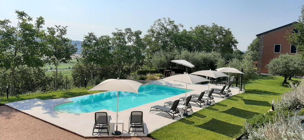 uma piscina com cadeiras e guarda-sóis num quintal em Ca' Dei Coci B&B em San Martino Buon Albergo