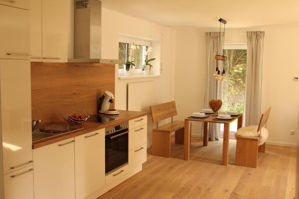 eine Küche mit weißen Schränken und ein Esszimmer in der Unterkunft Frankenwald Chalets - Ferienhaus Hans in Wilhelmsthal