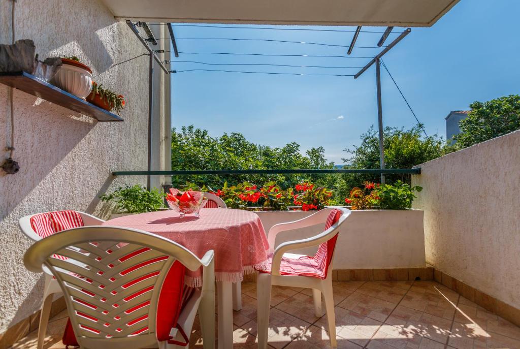 stół i krzesła na balkonie z kwiatami w obiekcie Apartment Dragica w Krku