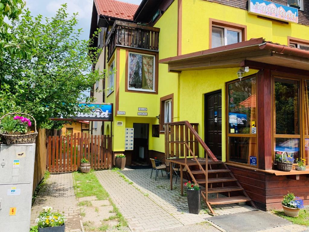 Casa amarilla con porche y valla de madera en Pension Aqualand, en Poprad