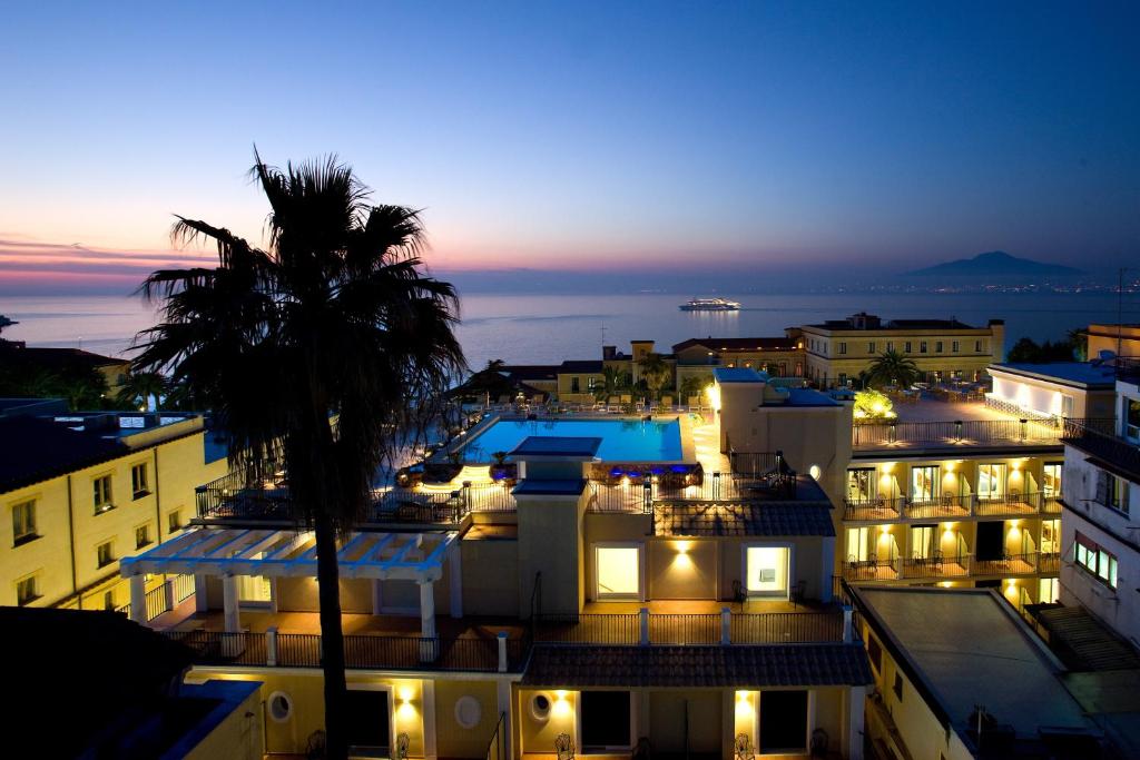 uma vista para uma cidade à noite com uma palmeira em Grand Hotel La Favorita em Sorrento