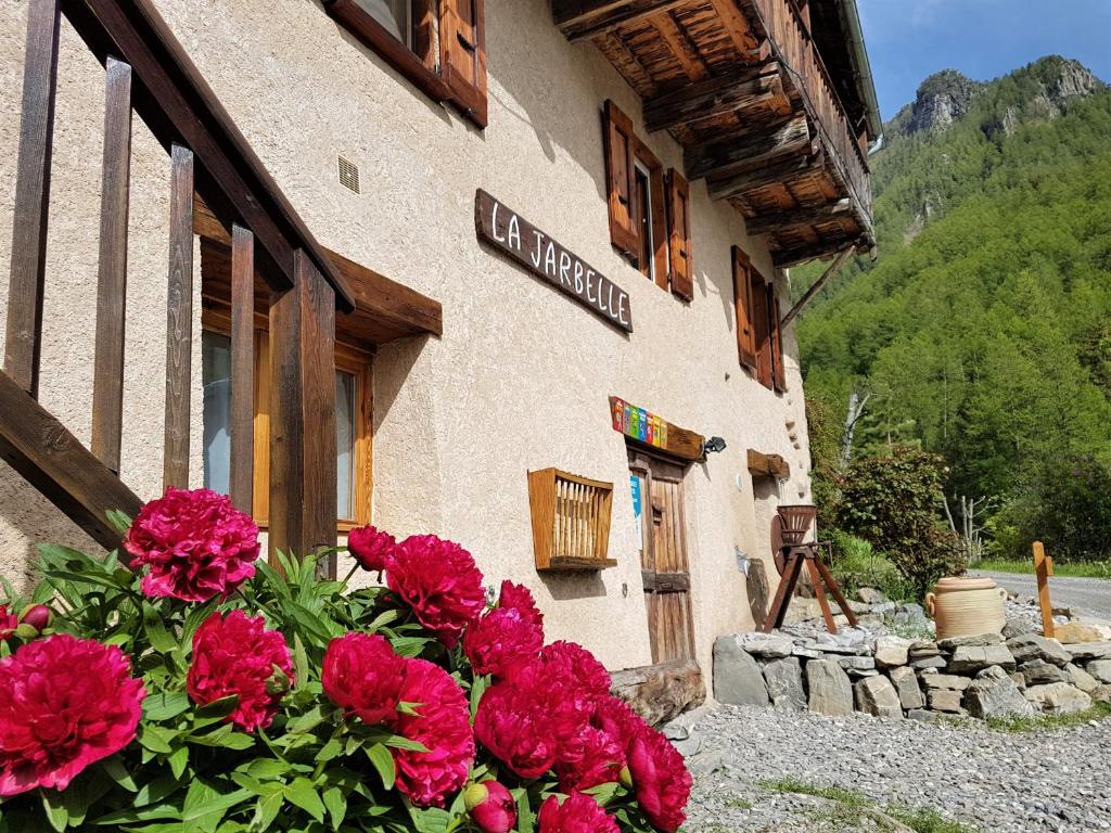 a building with red flowers in front of it at LA JARBELLE - Gîte et Spa in Les Orres