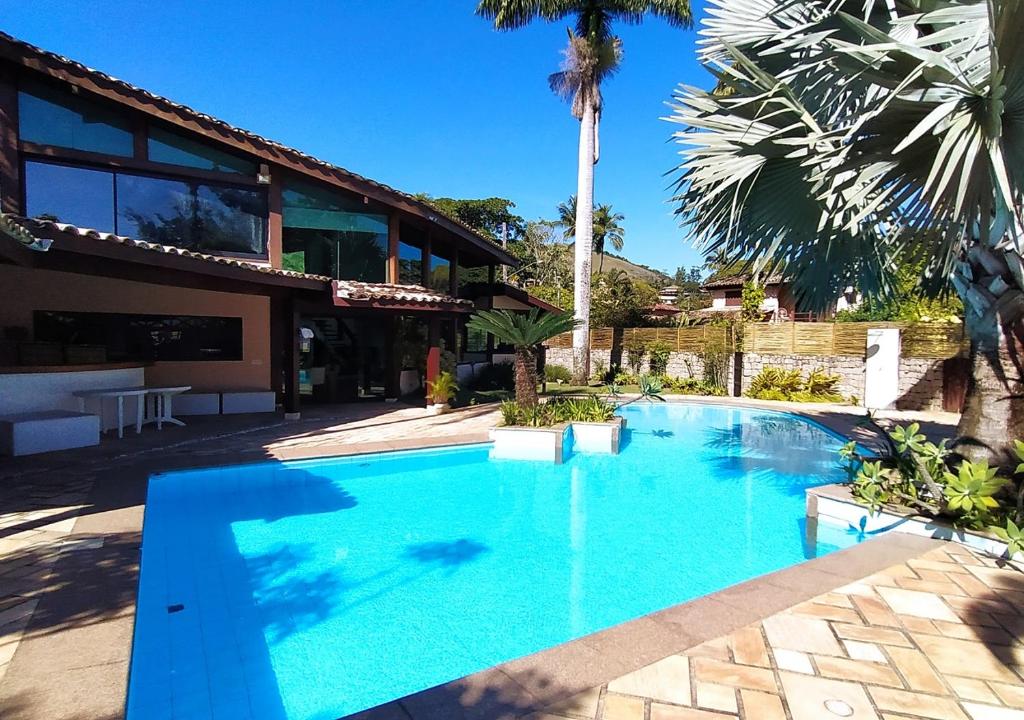 a large blue swimming pool in front of a house at Monalisa Guesthouse Pé na Areia Ilhabela in Ilhabela