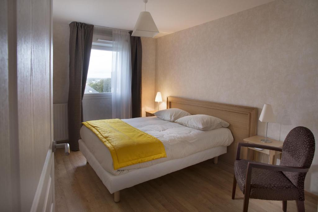 Un dormitorio con una cama con una manta amarilla. en Domitys Le Jardin d'Eole, en Lanester