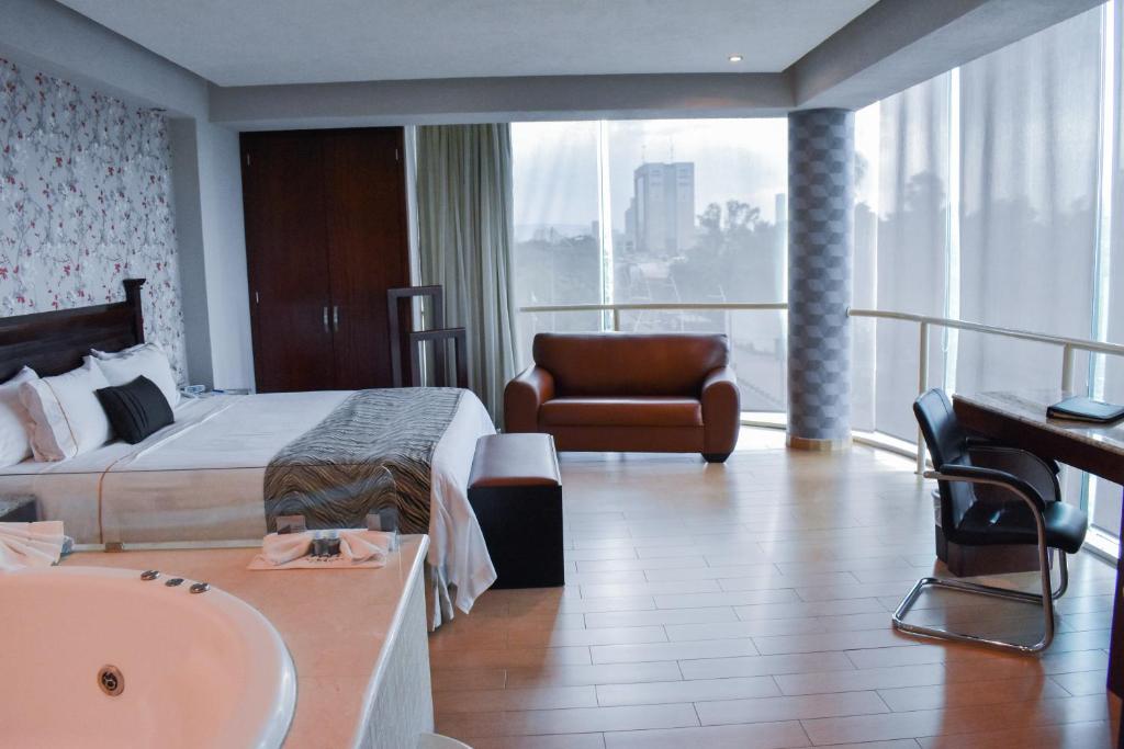 グアダラハラにあるホテル ポルト ベロのベッド、シンク、バスタブが備わるホテルルームです。