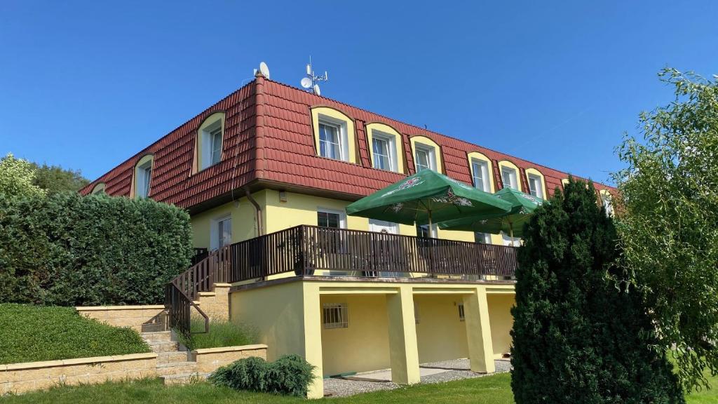 a house with a red roof and a balcony at Penzion Kamejk in Kamýk nad Vltavou