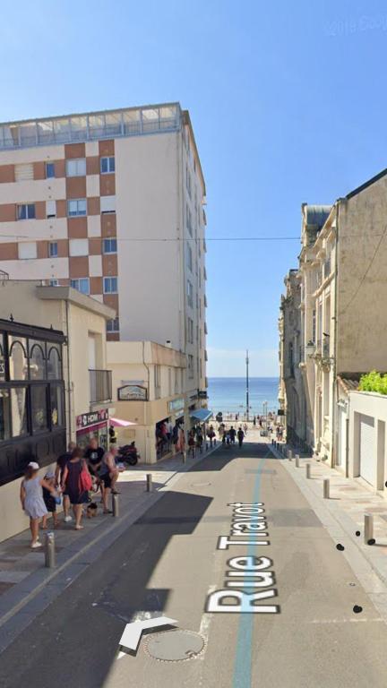 une rue urbaine vide avec des bâtiments et l'océan dans l'établissement Appartement T3 au coeur des sables d'Olonne, à Les Sables-dʼOlonne