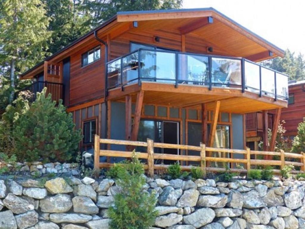 een groot houten huis met een stenen muur bij Fish Tales Cottage in Port Renfrew