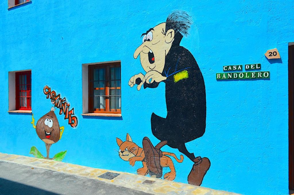 une fresque d'un homme marchant un chat sur un mur bleu dans l'établissement La Casa del Bandolero, à Júzcar